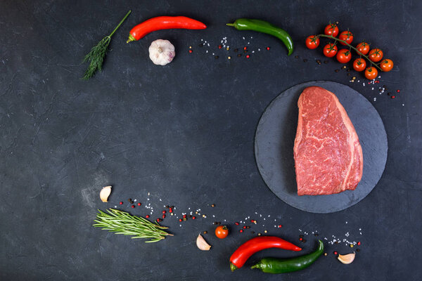 Raw fresh marbled meat and seasonings on dark background top view