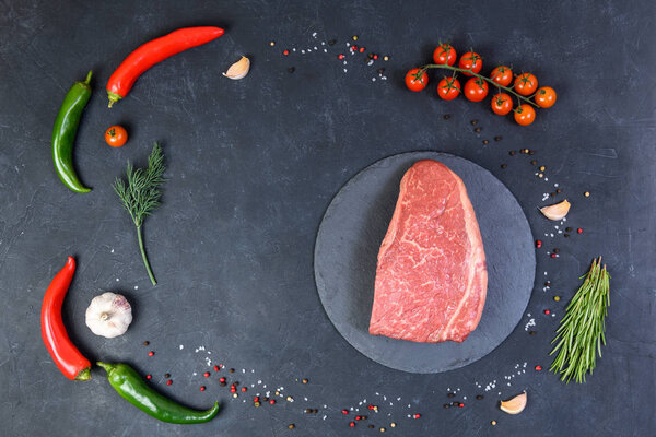 Raw fresh marbled meat and seasonings on dark background top view