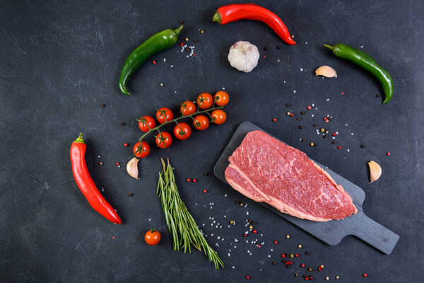Raw fresh marbled meat and seasonings on dark background top view