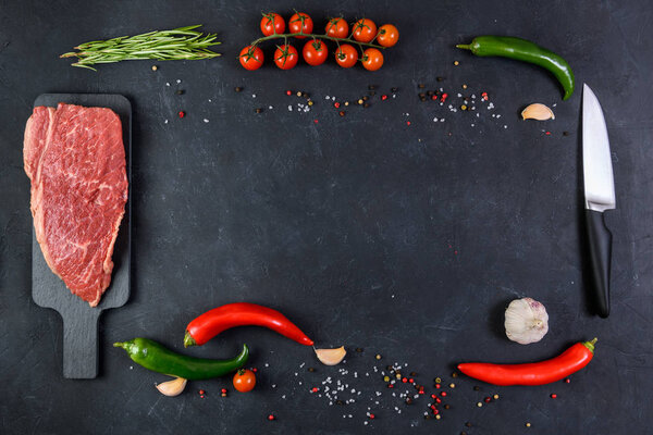 Raw fresh marbled meat and seasonings on dark background top view