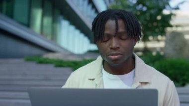 Dışarıda dizüstü bilgisayarla oturan sıkıntılı genç adam işten çıkarılma haberini aldıktan sonra şok ve üzüntüyle tepki verdi..