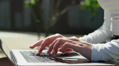 Doğal ışık altında dizüstü bilgisayarda klavyeyle yazı yazan kadın ellerini kapat.