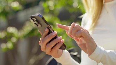 Doğal ışık altında dokunmatik ekranlı akıllı telefon kullanan kadın eller.