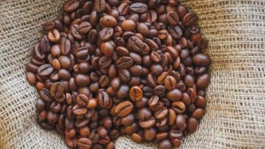 Doğal brown kahve çekirdekleri çuval bezi doku kavrulmuş. Sorunsuz döngü arka plan döndürme.