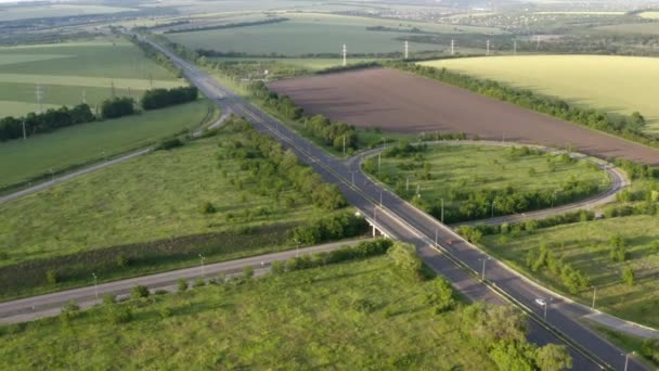 Images 4k du paysage avec autoroute asphaltée entre prairie et champ rural. Vue aérienne sur la route nationale à travers les champs verts par une journée ensoleillée d'été. Drone tourne la vidéo de la campagne.