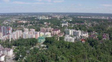 Güneşli yaz gününde şehir manzarası ve gökyüzü görüntüsü. Yeşil ağaçlar arasındaki kentsel binaların 4K videosu. Şehir merkezinin güzel manzarası.