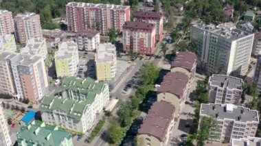 Evleri ve arabaları olan bir şehir caddesinin havadan görünüşü. Yeşil ağaçlar arasındaki modern binalar. Güneşli yaz gününde gökdelenlerle dolu şehir manzarası.