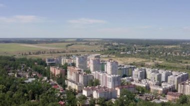 Şehirdeki ağaçlar arasındaki binaların 4K videosu. Şehir manzarasının güzel manzarası. Yazın güneşli bir günde mavi gökdelenli yeşil şehir manzarasının hava görüntüsü. 