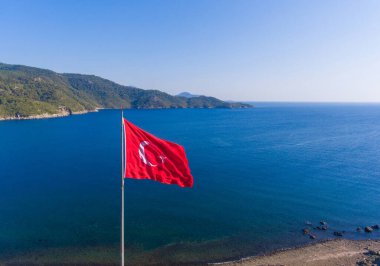 Denizin arka planında büyük bir kırmızı Türk bayrağı beliriyor.