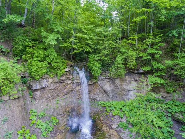 Long the flow of the waterfall cascading from the cliff. Aerial view. Drone photo.