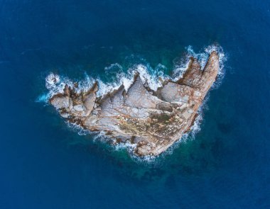 Deniz feneri olan küçük kayalık bir ada. Üst Manzara. Drone fotoğrafı.