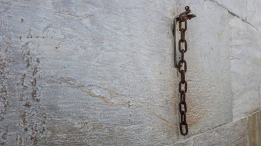 Paslı bir zincir parçası taş duvarda asılı..