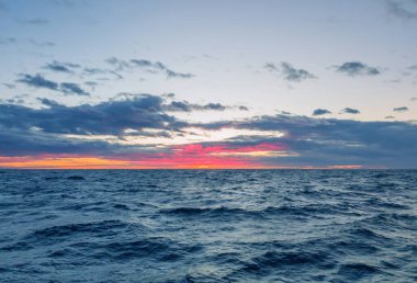 Açık denizde parlak kırmızı gün batımı.