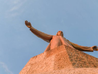 İsa 'nın taş heykeli Gün batımında kollarını açmış.