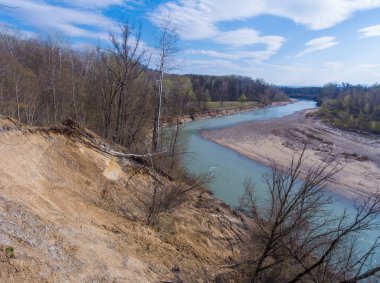 Nehirde kıvrıl ve ağaçlarla kaplı kil kıyıyı parçala. Drone fotoğrafı.