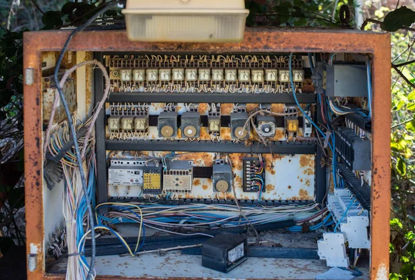 Rusty electric box with fuses and wires in the dump outside.