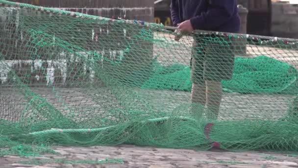 A port worker is fixing a green nylon fishing net outside. — Stock Footage Port Worker Fixing Green Nylon Fishing Net Royalty Free Stock Footage