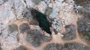 İnsansız hava aracını kayalık sahildeki delikte döndürmekten üst görüntü.