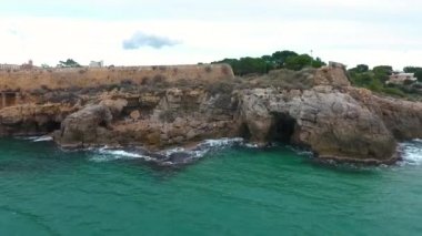Denizin kayalık kıyı manzarası ve Tarragona, İspanya 'daki eski kalenin taş duvarı.