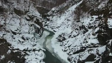 Vadinin dibindeki dağ nehri ve kayalıklarda buz saçakları..