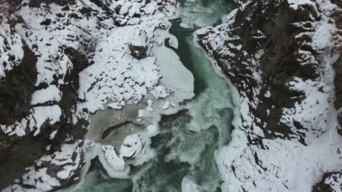 Karla kaplı bir vadinin dibinde hızlı akan turkuaz sular..