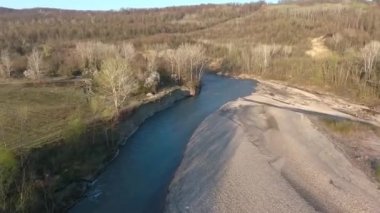 Nehir yatağı boyunca uçuyor. Tepedeki sonbahar ormanı.