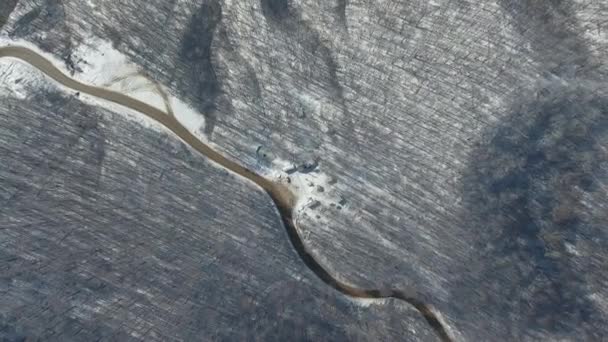 Vue de dessus d'une route sinueuse dans une forêt de montagne enneigée.