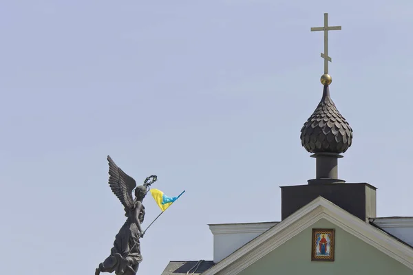 üst bir Ukrayna ile kanatlı bir figür ve kilise kapısı bir haç ile mavi gökyüzüne karşı bayrak.