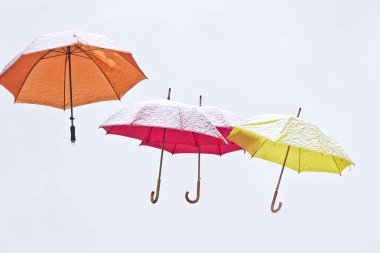 Çok renkli şemsiyeler karla kaplı fuarda kış gökyüzünde uçmak.