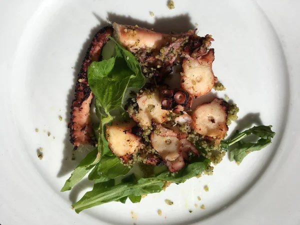 Luxury sliced cooked octopus plated with wilted greens a delicious dinner
