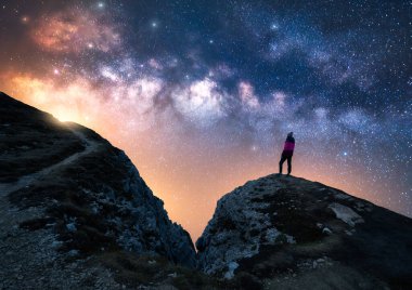 Parlayan Samanyolu ve yıldızlı gecede dağın zirvesinde bir kadın. Dolomitler, İtalya. Galaksi. Bir kızın siluetiyle uzay manzarası, kayalar, izler, parlak yıldızlı gökyüzü. Samanyolu ve yürüyüşçü. Gece manzarası
