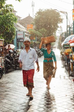 Ubud, Endonezya - 08 Mart 2016: Endonezya erkek ve kadın yağmur altında Ubud, Bali, Endonezya üzerinde 08 Mart 2016 sokakta yürüme geleneksel giysiler içinde