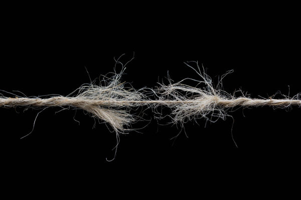 Frayed rope ready to break isolated on black background