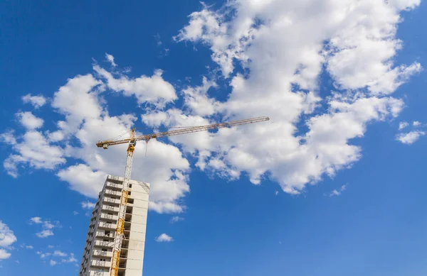 Construction crane building a building, the background sky and clouds