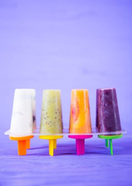 Dört farklı meyveli ve berry dondurma leylak arka plan üzerinde renkli formları. Yaz canlı sulu tatlı. Çeşitli şerbetler ayarla.