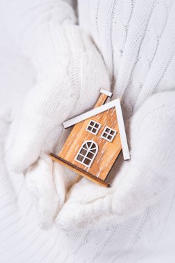 Tatlı beyaz Örme Eldivenler küçük kış oyuncak ev tutan eller. Güzel evim kavramı.