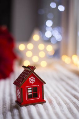 Gün ışığında beyaz örme kumaş oyuncak kırmızı ahşap evle sıcak garland bokeh arka plan üzerinde. Festival sihirli ışıklar. Yeni yıl tatil kompozisyon. Tatlı ev concept.