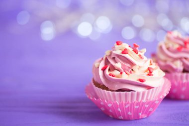 Mor bokeh arka plan üzerinde küçük kalpler closeup iki kek krem pembe ve beyaz top ile süslenmiş. Sevgililer günü tatlı.