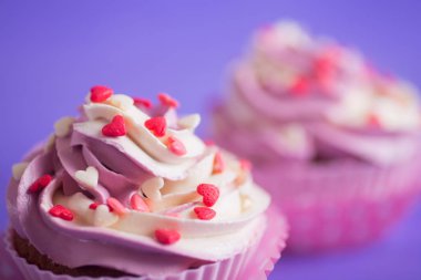 Mor zemin üzerine küçük kalpler closeup iki kek krem pembe ve beyaz top ile süslenmiş. Sevgililer günü tatlı.