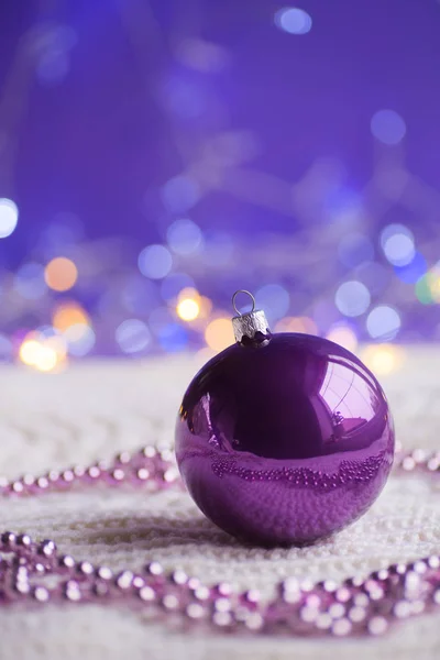 紫色圣诞球和珠子在白色针织织品在紫色背景与温暖的 Bokeh 新年贺卡 圣诞装饰 — 图库照片#