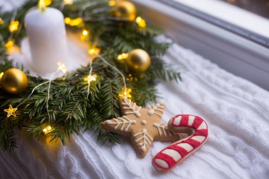 Noel gingerbread altın top, beyaz mum ve sıcak çelenk ışık şenlikli dekorasyon yakınındaki yıldız ve karamel baston şeklinde. Yeni yıl ev yapımı kurabiye.