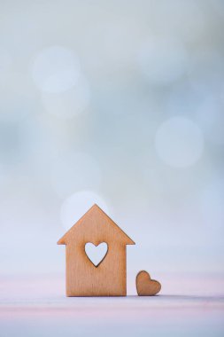 Pastel ışık bokeh arka plan üzerinde kalp şeklinde deliği olan evin ahşap simgesi. Romantik kart. Güzel evim kavramı.