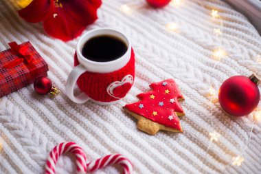 Örme rahat fincan çay ve Noel gingerbread kış dekorasyonu ile çevrili beyaz örme şal üzerinde. Nergis zambağı, Noel topları ve gün ışığından yararlanma penceresinde yakınındaki hediye kutusu. Yeni yıl tatil kompozisyon.