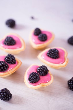 Tatlı pembe berry yoğurt böğürtlen içinde beş kalp şeklinde tartlets süslenmiş. İhale kadın romantik tatlı.