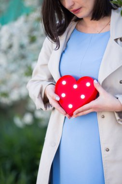 Genç erkek holding kırmızı parlayan Led kalple bulanık bahar arka plan eller. Kadın için romantik hediye.