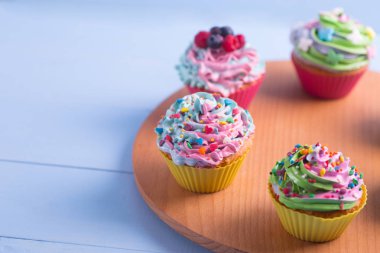 Sprinkles ahşap yuvarlak masa ile dekore edilmiş kapatmak farklı renkli kek. Çok renkli pastel tatlılar.