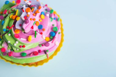 Tatlı kek krem çok renkli ile üst mavi arka plan üzerinde renkli sprinkles. Doğum günü partisinde veya Noel kek.