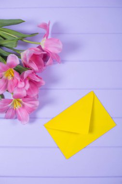 Canlı sarı zarf leylak ahşap arka plan üzerinde düz Pembe Lale ihale buket bahar ile yatıyordu. Kart kopya alanı ile.