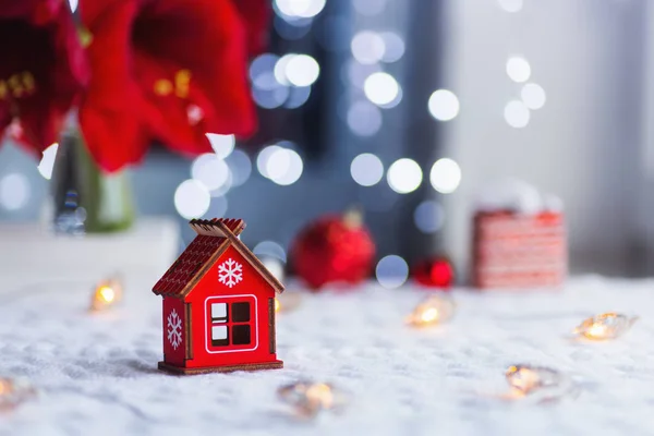 Close up red Christmas wooden house with snowflake indoor with home festive decor and blurred bokeh background in daylight . — стоковое фото
