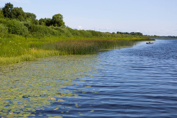 Forest lake with water lilies and boat and footbridge